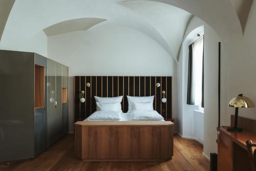 1 dormitorio con 1 cama y suelo de madera en Arthotel Lasserhaus en Brixen