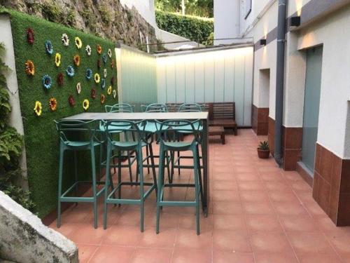 un patio con tavolo, sedie e fiori appesi a un muro di San Sebastián Fresh !! Vivienda & Terraza a San Sebastián
