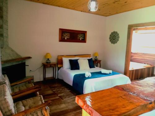 a bedroom with a large bed and a fireplace at Recanto KAIRÓS in Visconde De Maua