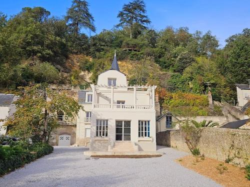une grande maison blanche avec une église sur une colline dans l'établissement Le Petit Versailles Loire Tours, à Rochecorbon