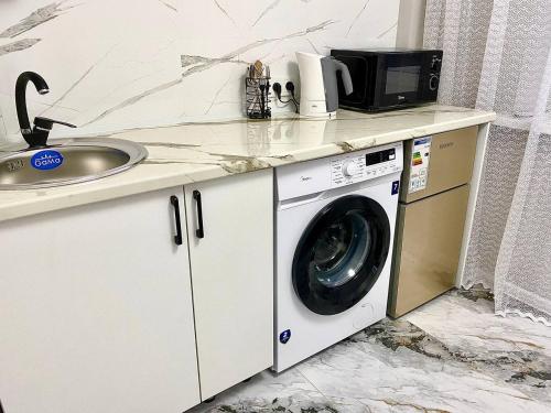 a washing machine sitting on a counter next to a sink at Апартаменты аэропорт 1 in (( Turksib ))