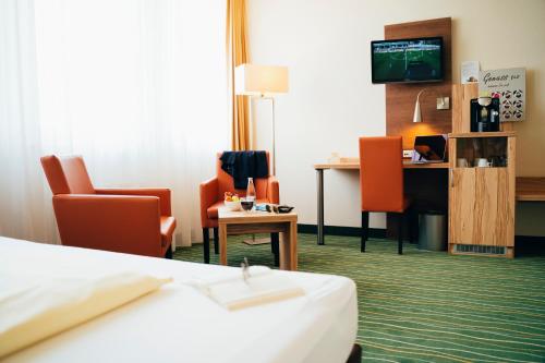 a hotel room with a bed and a desk and chairs at business & conference Sporthotel Großwallstadt in Großwallstadt