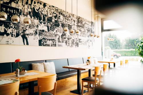 a restaurant with wooden tables and chairs and a large picture on the wall at business & conference Sporthotel Großwallstadt in Großwallstadt