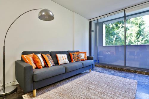 a living room with a blue couch with orange pillows at CBD Harbour Retreat - Lovely 2BR Home in Sydney