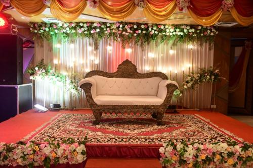 a couch in the middle of a stage with flowers at Hotel Gurveer Royal in Lucknow