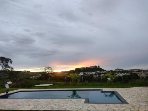 a swimming pool with a sunset in the background at Rancho Pôr do Sol in Piumhi