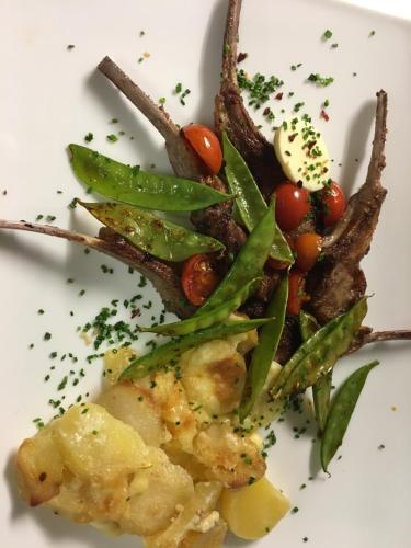 a white plate of food with vegetables and meat at Alpenhof Landhotel Restaurant in Oberaudorf