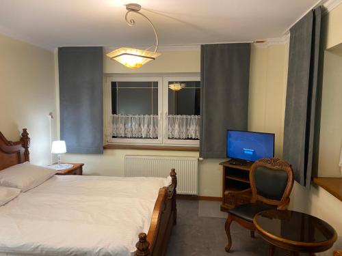 a bedroom with a bed and a desk with a television at Noclegi Prestige in Siewierz