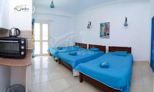 een kamer met vier blauwe bedden en een televisie bij Dolphina hotel & Restaurant in Dahab