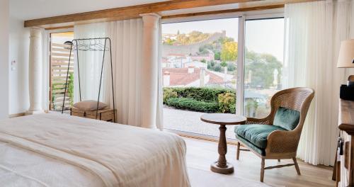 um quarto com uma cama e uma grande janela em Hotel Real d Obidos em Óbidos