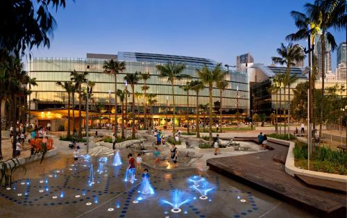 a group of people standing around a fountain in front of a building at CBD Harbour Retreat - Lovely 2BR Home in Sydney