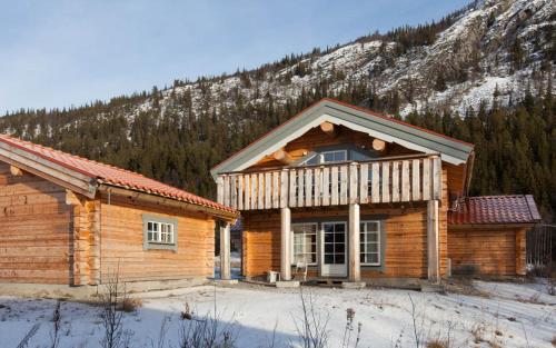a log cabin in the snow in front of a mountain at Timmervillan in Funäsdalen