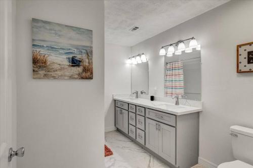 een witte badkamer met een wastafel en een spiegel bij Updated 4 bedroom home in Oragnefield in Orange