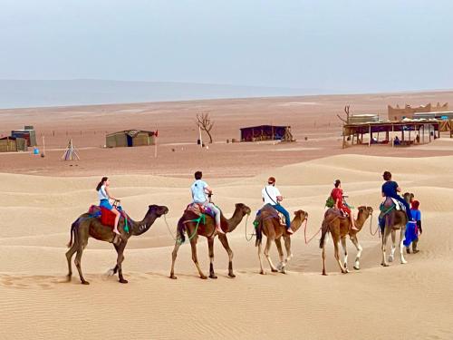 Mhamid Sahara Golden Dunes Camp - Chant Du Sable في Mhamid: مجموعة من الناس يركبون الخيول في الصحراء