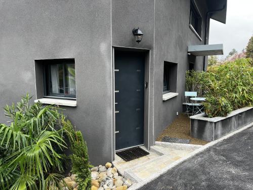 un edificio con una puerta azul y algunas plantas en Superbe appartement entre lac et montagne., en Veyrier-du-Lac