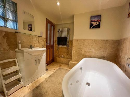 a bathroom with a bath tub and a sink and a bath tub at Well Furnished Holiday Cottage In The Heart Of Docking, Norfolk Ref 99009ht in Docking