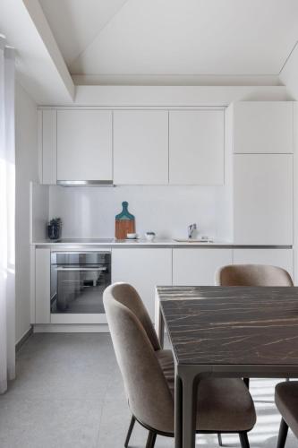 a kitchen with white cabinets and a table and chairs at 3 VIE Restaurant & Rooms in Acquarossa