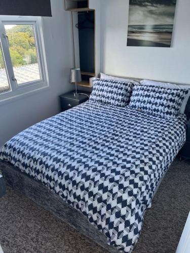 a bed with a blue and white comforter in a bedroom at DRIFTWOOD LODGE please note the facilities at the holiday park are seasonal March to November in Bideford