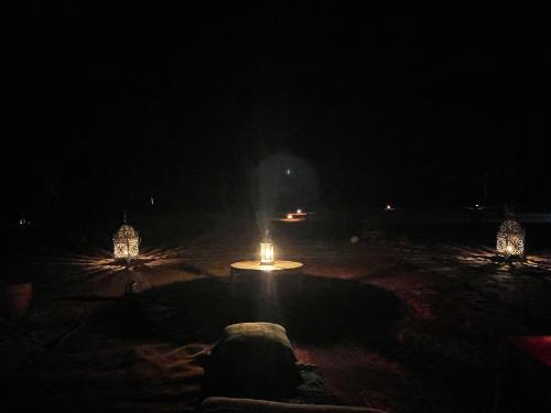 a lit table with a candle in the dark at Mhamid Sahara Camp Activities - Le Chant du Sable in Mhamid