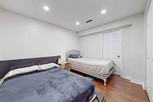 a bedroom with two beds and a white wall at Executive Apartment - 2 Bedrooms in Barrie