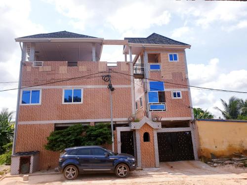 un bâtiment avec une voiture garée devant lui dans l'établissement Immeuble Adam, à Lomé