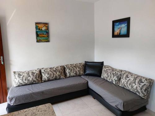 a couch in a living room with two pictures on the wall at Ap Vista Mar em Caraguatatuba in Caraguatatuba