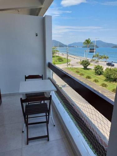a table and chairs on a balcony with a view of the ocean at Ap Vista Mar em Caraguatatuba in Caraguatatuba