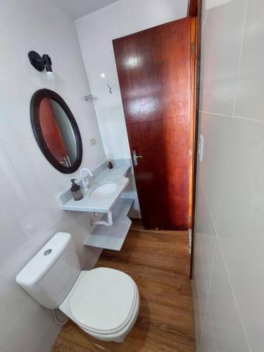 a bathroom with a toilet and a sink and a mirror at Ap Vista Mar em Caraguatatuba in Caraguatatuba