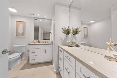 a white bathroom with a toilet and a sink at Amazing BahiaMar beachfront 2 steps from amenities in South Padre Island