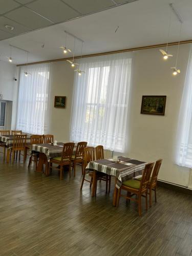 uma sala de jantar com mesas, cadeiras e janelas em Готель em Bila Tserkva