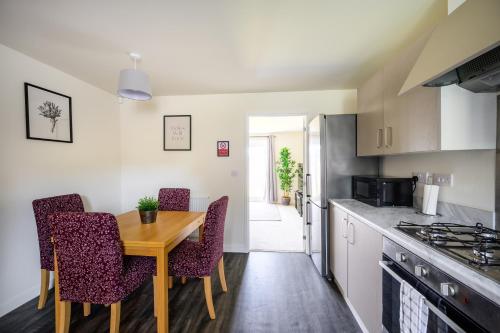 a kitchen with a wooden table and some chairs at Wykebeck Mount by Our Home Short Stays in Killingbeck