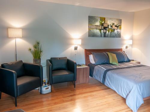 a bedroom with a bed and two chairs at Résidence Touristique Chicoutimi in Saguenay