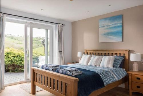 a bedroom with a bed and a sliding glass door at Seaside Retreat with Stunning Sea Views in Talland