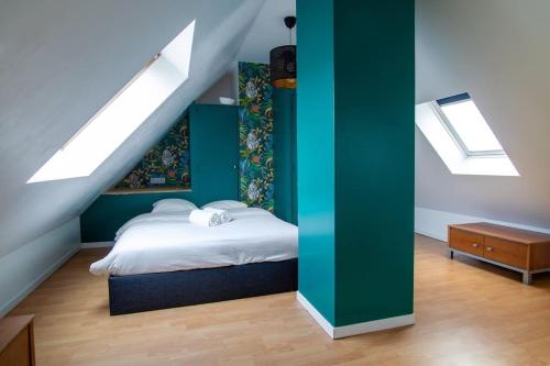 een slaapkamer met een bed met een groene muur en dakramen bij Le Molsheim - Grand appartement proche Musée dArt Moderne in Straatsburg
