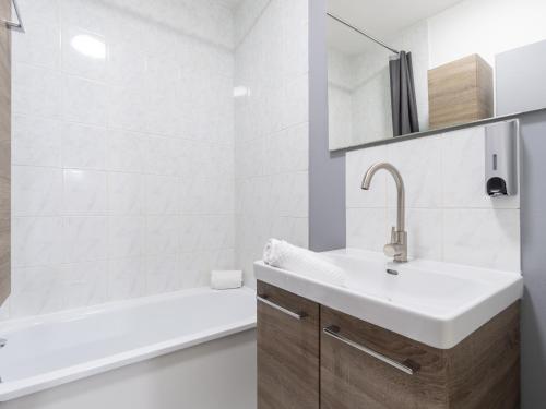 ヴィエンヌにあるLa Petite Histoireの洗面台とバスタブのある白いバスルーム