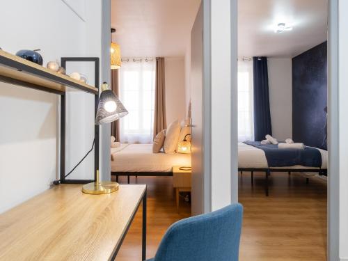 Habitación con 2 camas y mesa con lámpara. en La Petite Histoire, en Vienne