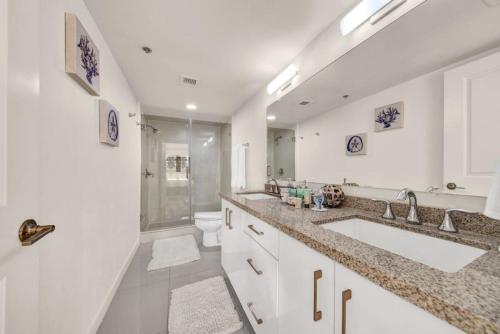 Baño blanco con 2 lavabos y aseo en Luxury Beachfront Condo With Amazing Sunset Views, en South Padre Island