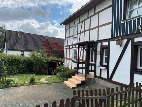 a white and black house with a wooden fence at 120 Jahre altes Fachwerkhaus in Bachenberg