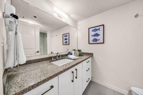 une salle de bain blanche avec un lavabo et un miroir dans l'établissement Jackpot Beachfront Condo With Amazing Sunset Views, à South Padre Island