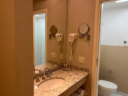 a bathroom with a sink and a phone on the wall at Flat Barra da tijuca in Rio de Janeiro