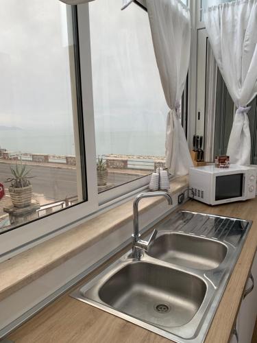 a kitchen sink with a microwave and a window at Casa Vacanze Formia in Formia