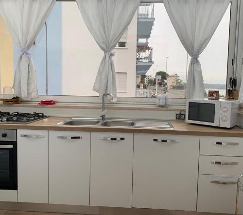 a kitchen with white cabinets and a sink and a window at Casa Vacanze Formia in Formia