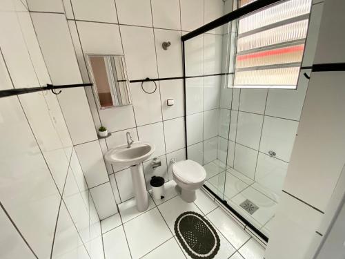 a white bathroom with a sink and a toilet at Apto Santos Gonzaga 50mtrs Praia in Santos