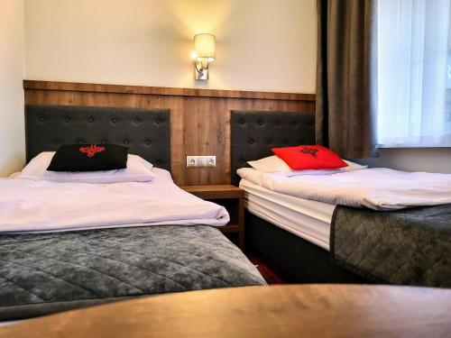 two beds in a hotel room with red pillows at Magnolia in Zakopane