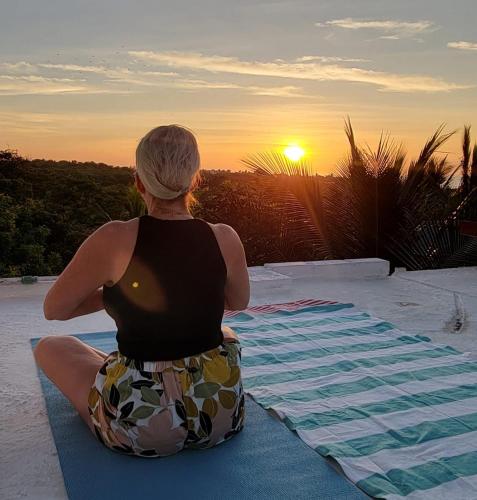 a woman sitting on a mat watching the sunset at OCEAN OASIS HOTEL - adult only, four casitas boutique resort in Playa Agua Blanca