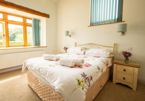 a bedroom with a bed with white sheets and a window at Sychpant Barn in Velindre