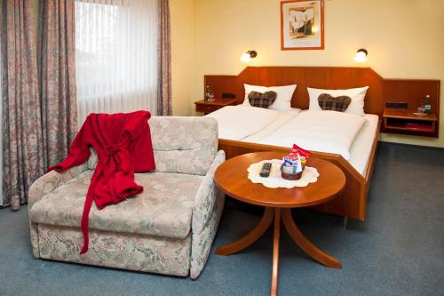 ein Schlafzimmer mit einem Bett, einem Sofa und einem Stuhl in der Unterkunft Hotel bei Liebe's in Erlenbach am Main