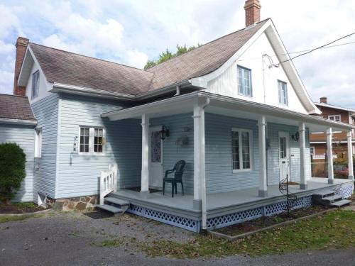 ein weißes Haus mit einer Veranda mit einem Stuhl darauf in der Unterkunft La Maison Gagnon in Saguenay