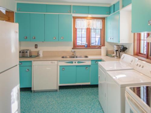 a blue kitchen with blue cabinets and a sink at La Maison Gagnon in Saguenay