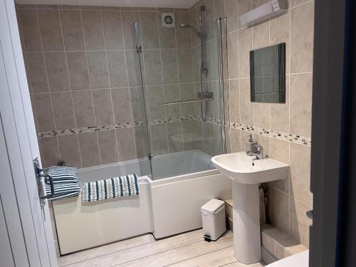 ein Bad mit einer Badewanne, einem Waschbecken und einer Dusche in der Unterkunft Poachers Hut - Captivating 1-bed Cottage Shorwell in Shorwell